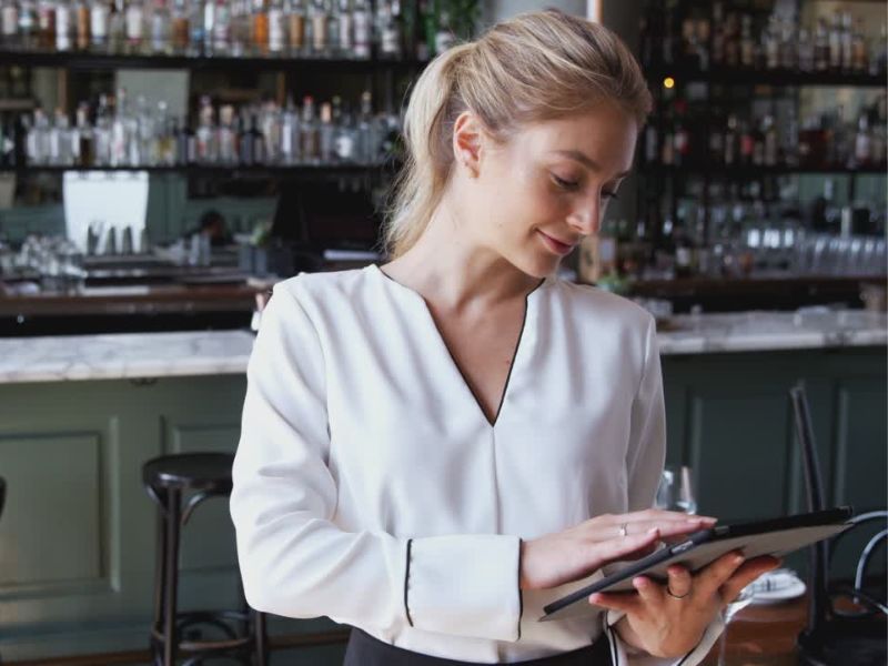 Devojka drži tablet u rukama i stoji u restoranu